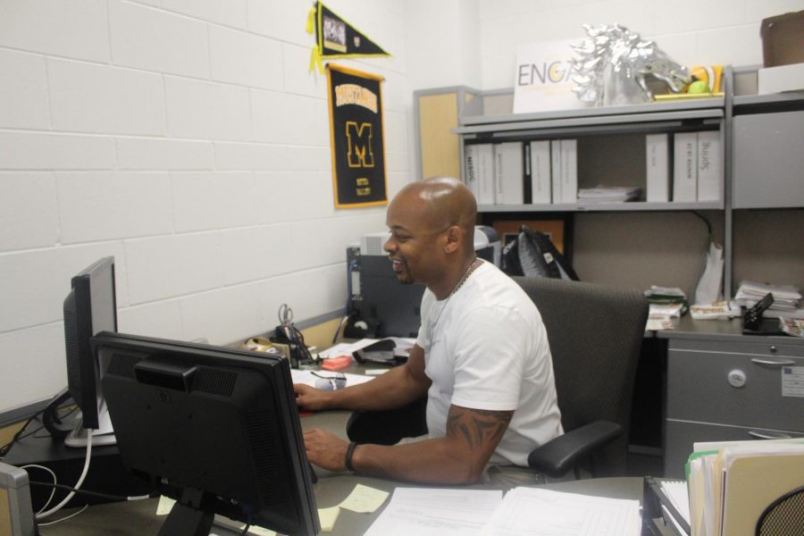 Athletic Director Jason Ward works at his desk to plan and transition teams from summer practices to competition season. 