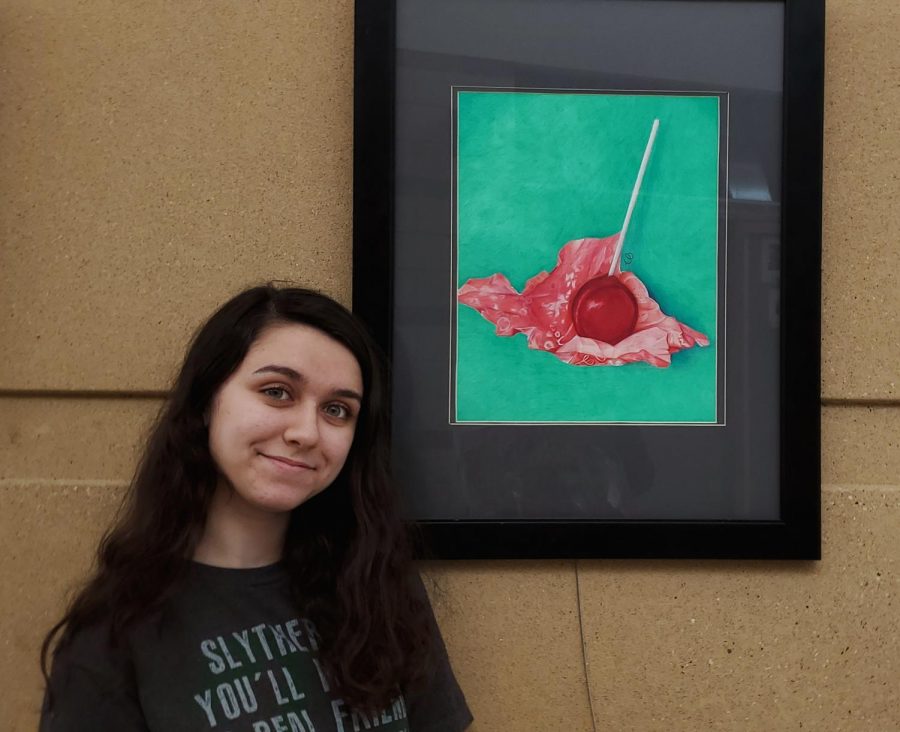 Cheyenne Brown stands with her colored pencil drawing
