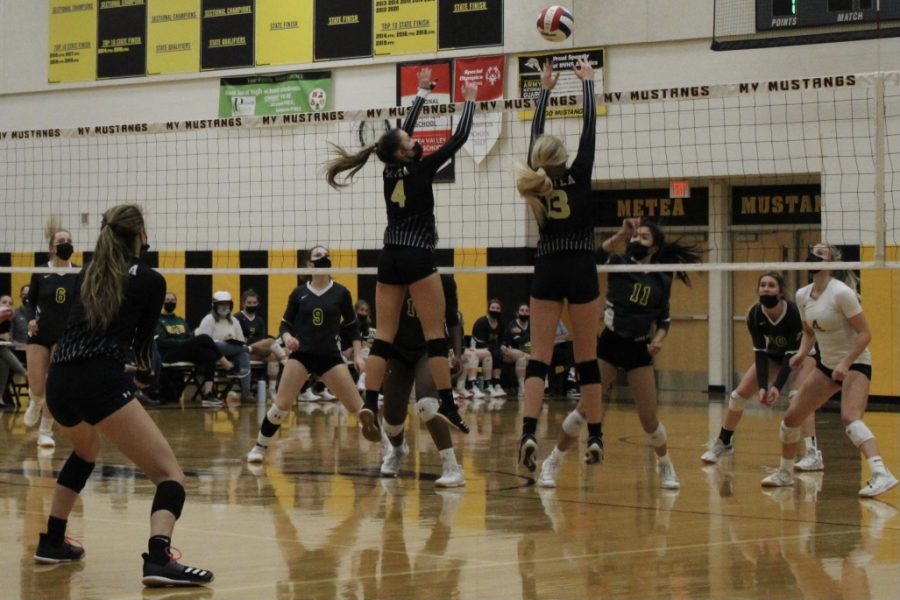 Middle hitters Jessical Williams (#4) and Nicole Amrhein (#13) go in for a block against a hit made by Waubonsie. 