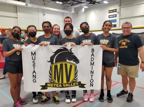 Badminton players take a photo with a Metea banner.