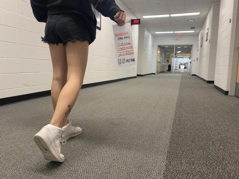 A student walks to the restroom holding a required pass.