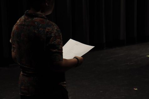 A student reads a script provided by their theater instructor.