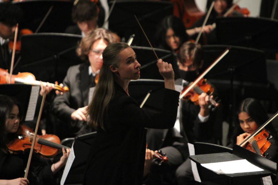 The conductor leads the orchestra during the collage performance.