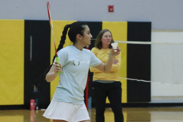 A badminton player holds the birdie as she prepares to serve.