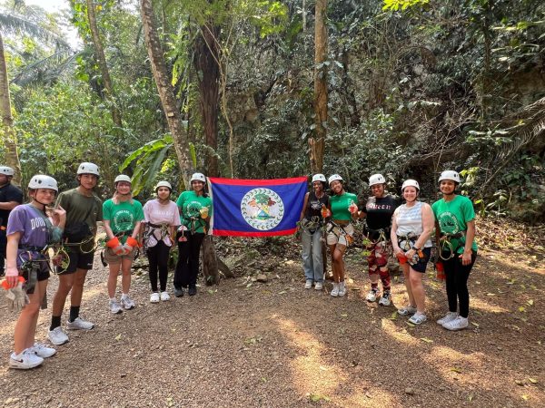 Belize travelers pose with the Belize flag before going ziplining.