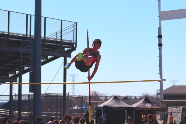 Naperville central student athlete gracefully pole-vaults without touching the bar. 
