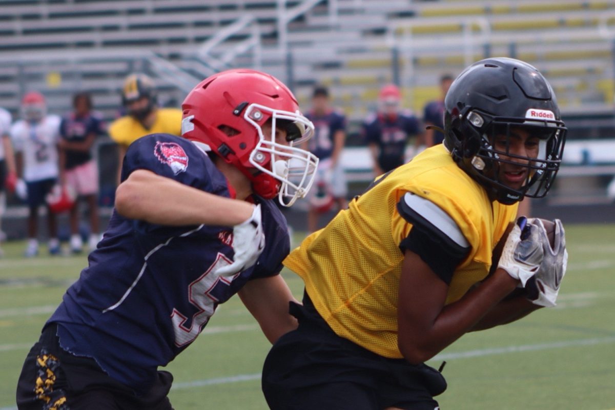 Student athlete from Metea shields the football from a West Aurora athlete.