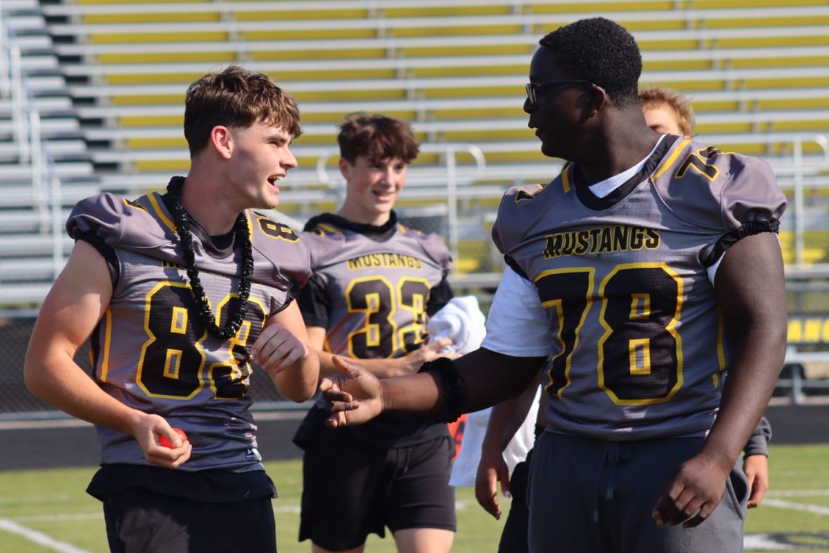 Eli Peterson and Okiki Oyekanmi cheer together after they win a game during the assembly. 