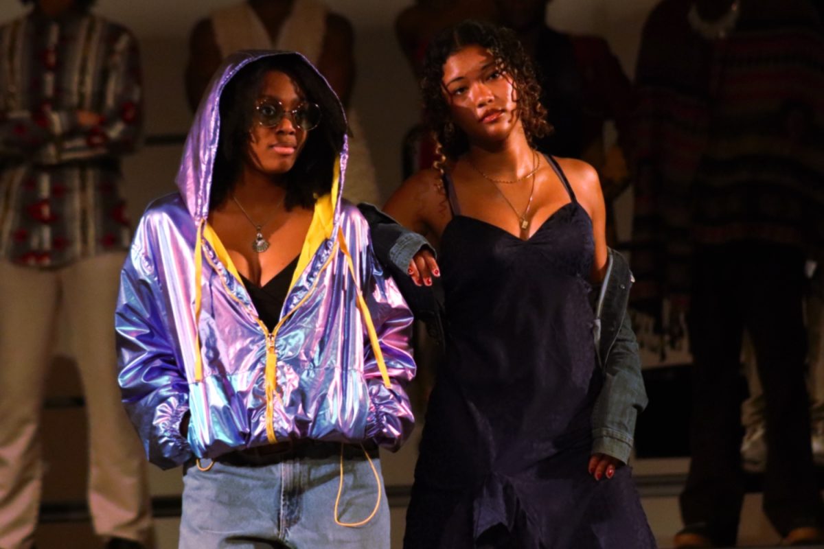 Two students walk down the runway of the Afrofuturism showcase, displaying high fashion and the creativity of other students. 