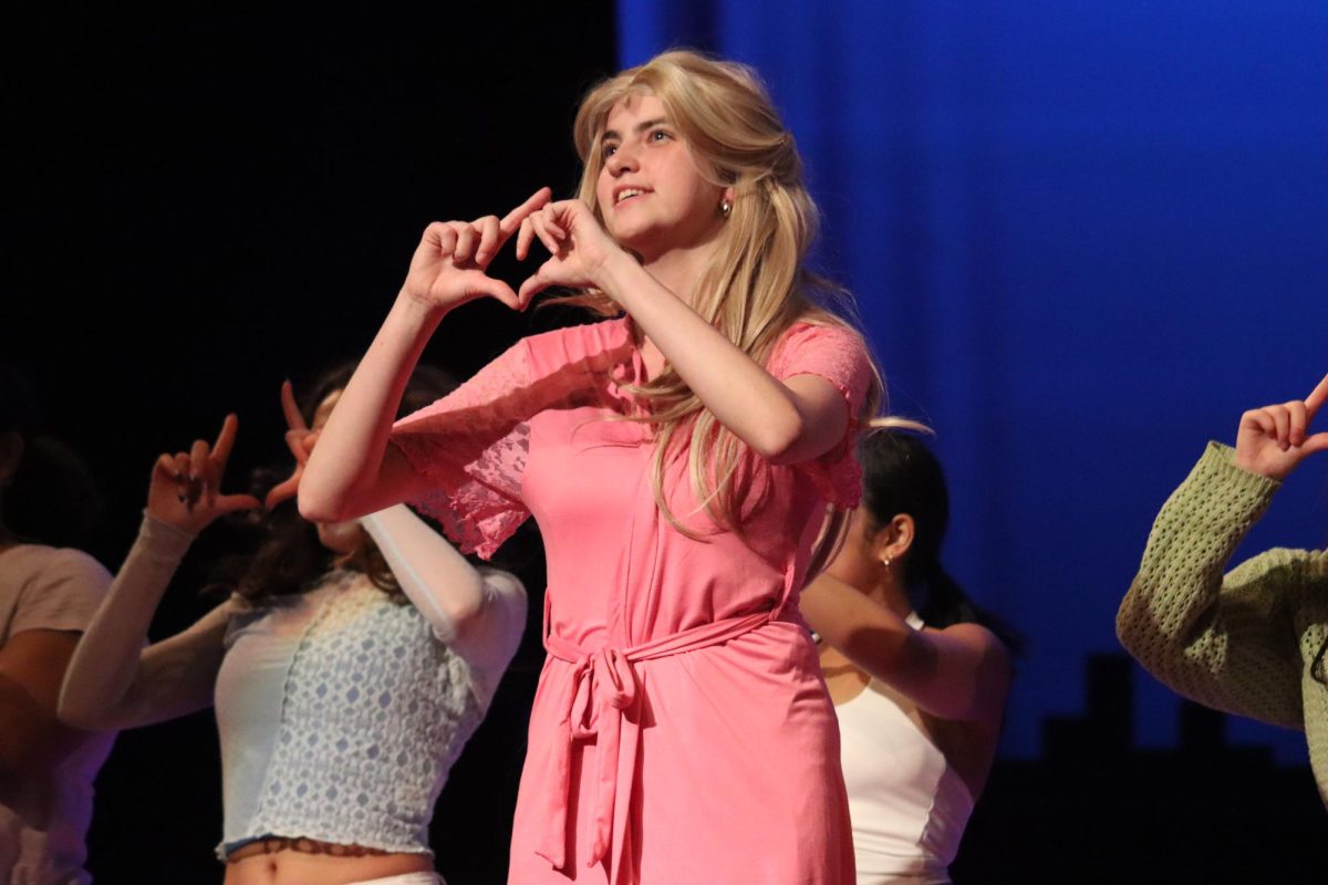 Elle Woods's understudy, Grayce Hunt, performs the song 'What you want,' making the symbol of the sorority Delta Nu.