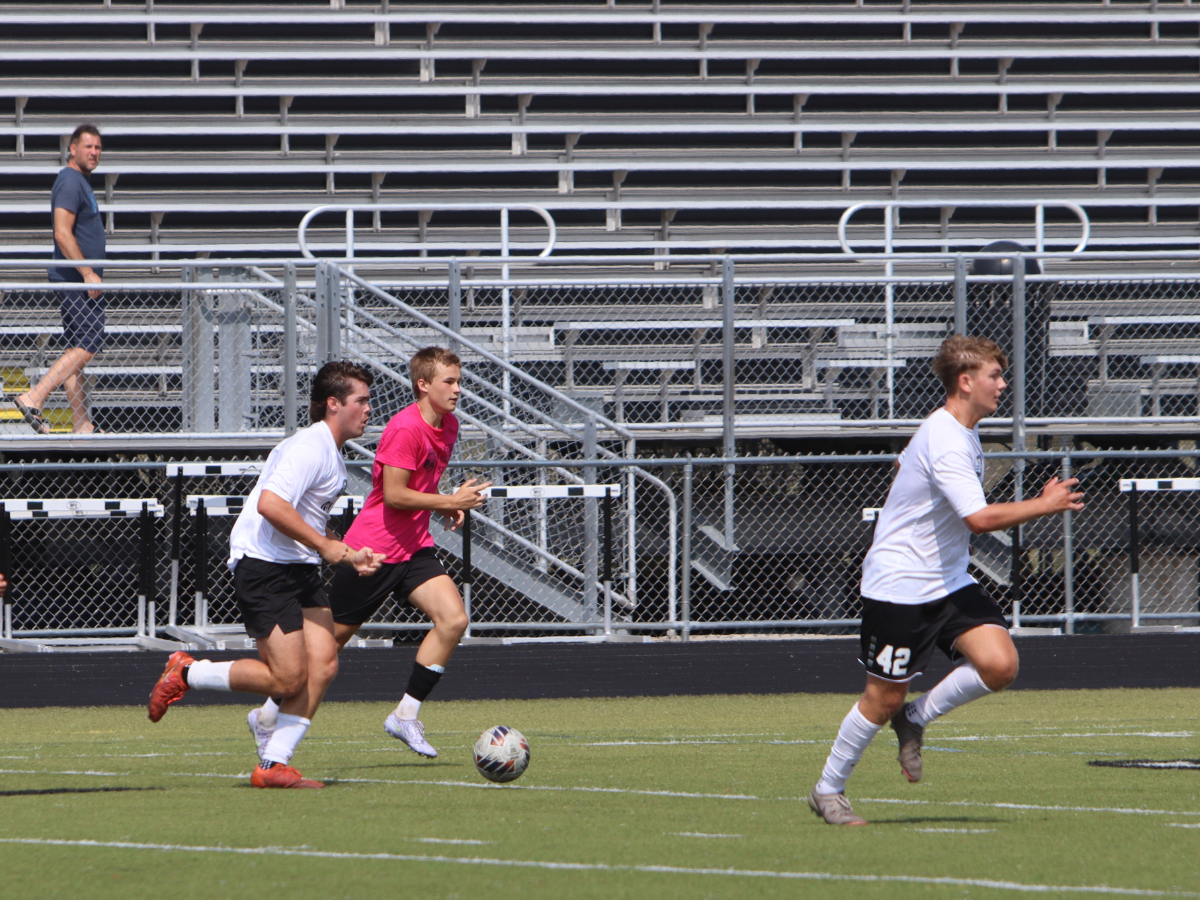 Geneva player dribbles soccer ball throughout the turf.