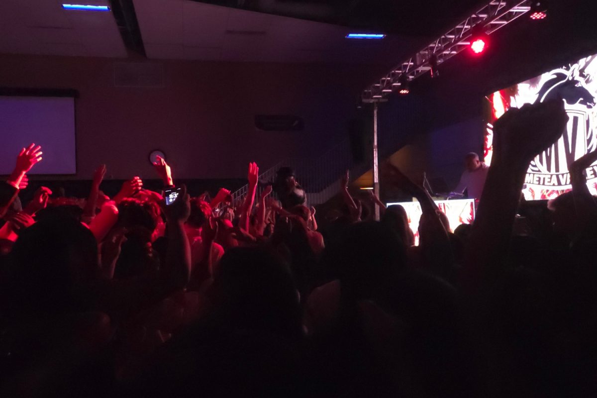 Students raise their hands with enthusiasm while dancing along to the music.