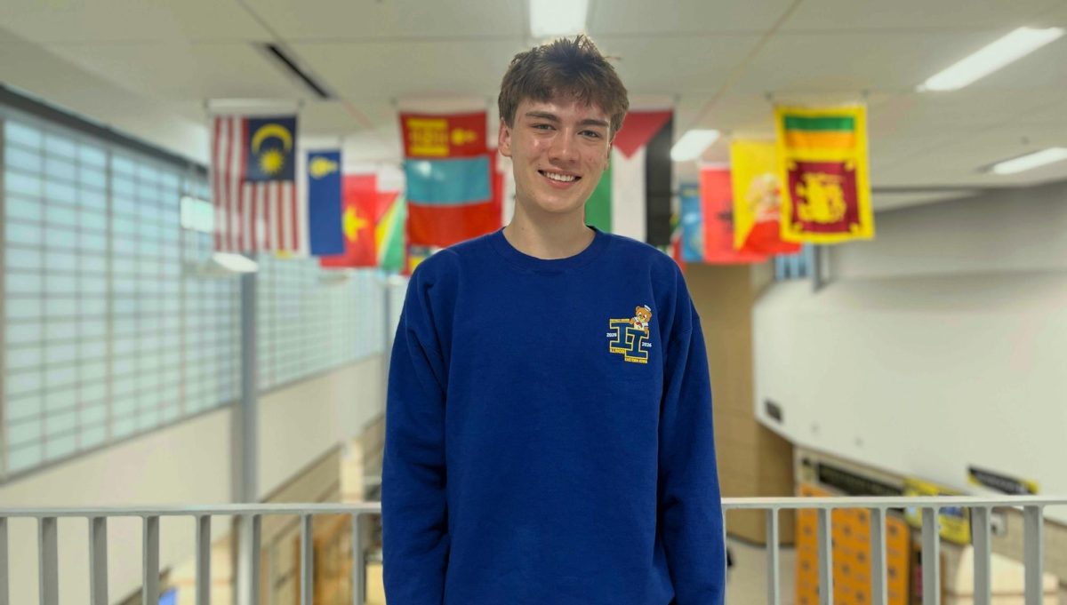 Senior Henry Graunke standing in front of Metea’s flag gallery.