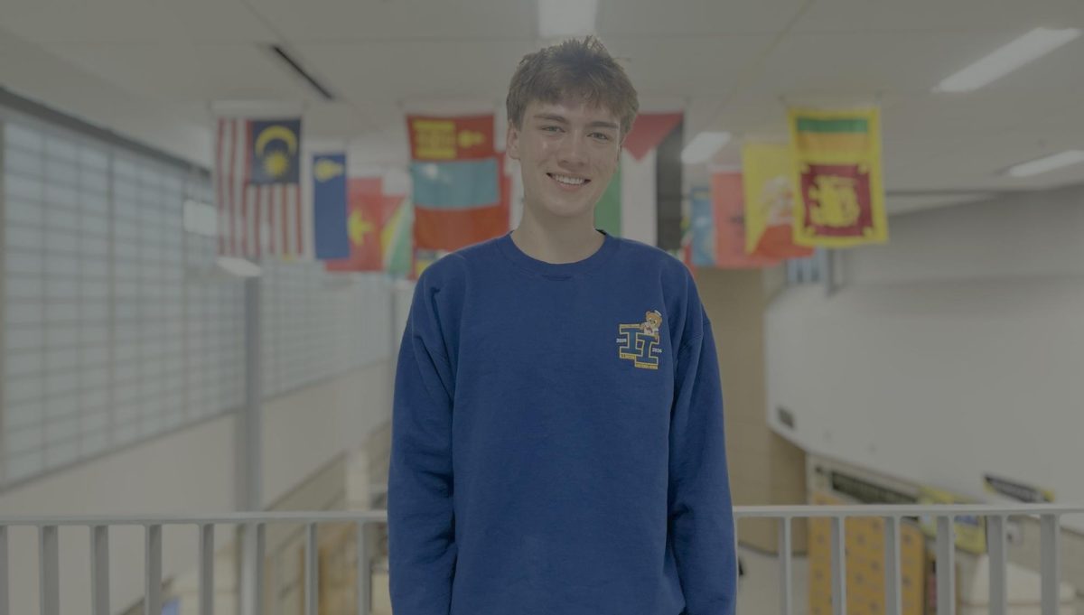 Senior Henry Graunke standing in front of Metea’s flag gallery.