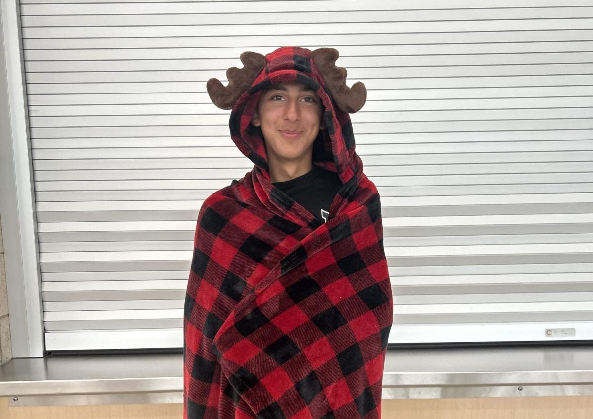 Junior Noah Ali stays comfortable wearing a plaid blanket over his pajamas.