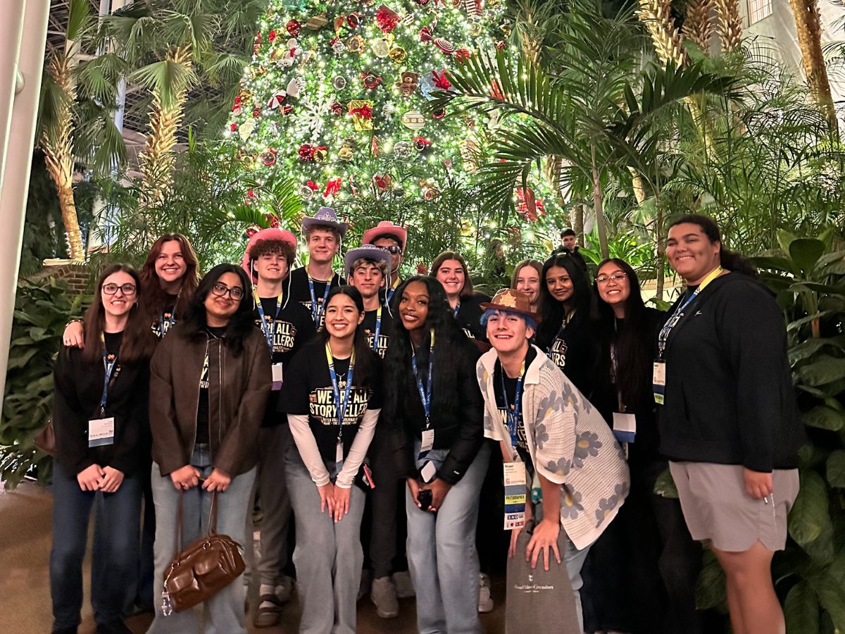 The journalism team poses in front of the giant Christmas tree in the delta atrium.
