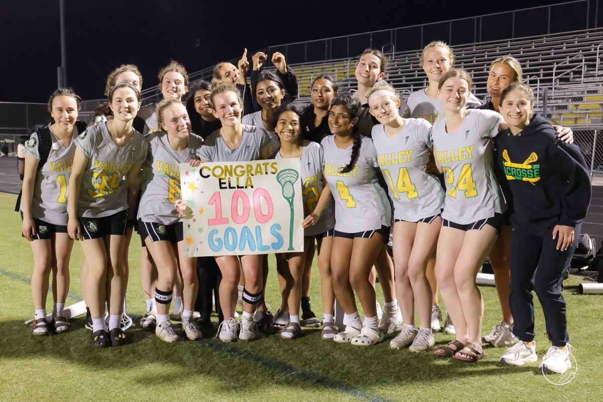 Ella Guzaski and the varsity lacrosse team celebrate 100 goals within a group photo.